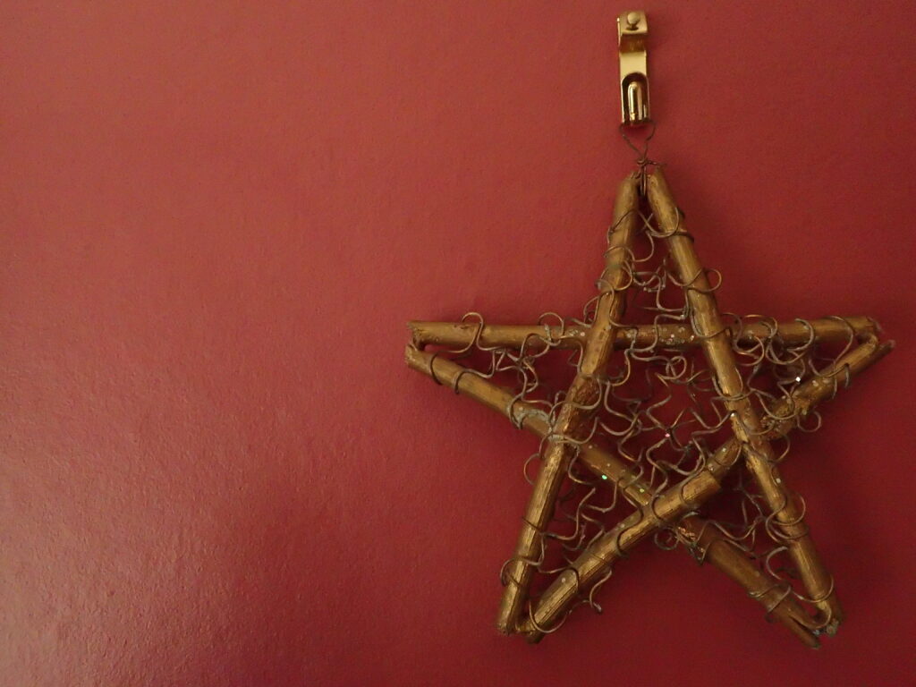 Wooden Pentacle hanging on a burgandy wall.